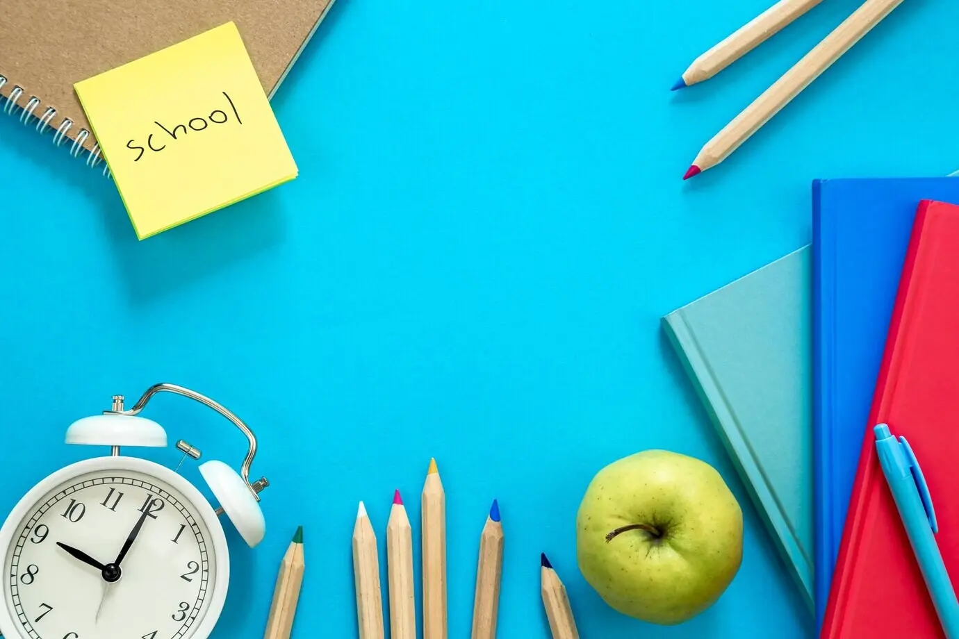 Komposition in Draufsicht mit bunten Lernmaterialien auf blauem Hintergrund.